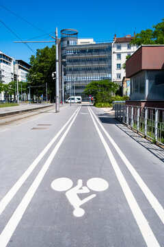 Bike lane in Lyon, France stretches between white markings and tram rails, guiding urban mobility through a quiet street under clear sky