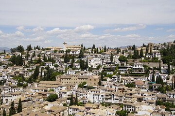 Obraz premium This photograph shows the Albaicín, a historic district of Granada, Spain. It is known for its traditional whitewashed houses, known as carmenes, scattered across a steep hillside. 