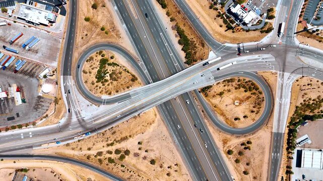 Rising over the intersection with bridge and loops. Lots of trucks are parked nearby the lively roads.
