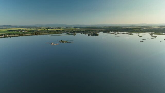 Aerial View of Calm Lake with Forest Shoreline and Mountains at Sunset in Poland