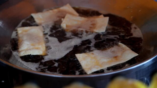 View of traditional Brazilian pastel being deep-fried in hot oil until golden brown at a street market in Rio de Janeiro, Rio de Janeiro, Brazil.