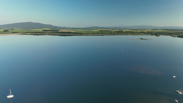 Aerial View of Calm Lake with Forest Shoreline and Mountains at Sunset in Poland