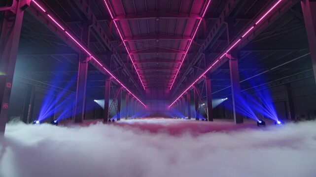 Industrial warehouse, empty hangar and neon lights with smoke for music video, event production and concert stage. Cinematic space, blue spotlights and pink glow in dark room with fog, and backdrop