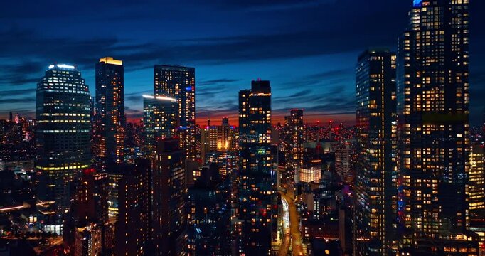 Going up along the gorgeous high-rises reflecting sparkling lights of the city at night. Spectacular view on New York City, USA from drone.