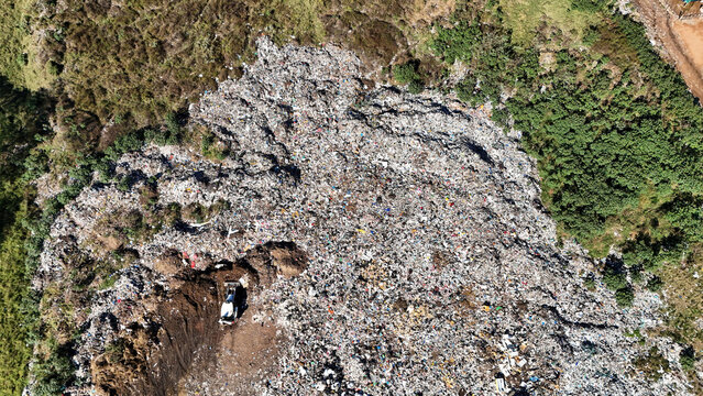 Aerial view of a large landfill site with a white truck working on a pile of waste surrounded by green vegetation in Vaalwater, Limpopo, South Africa.