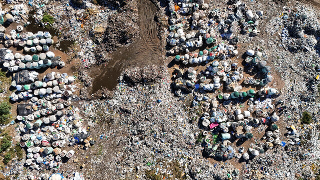 Aerial view of a large landfill site with organized rows of white waste bags and scattered trash on the ground in Vaalwater, Limpopo, South Africa.