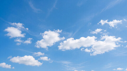 Scattered fluffy white cumulus clouds drift across a wide, vibrant blue sky on a clear and sunny day. © Trong