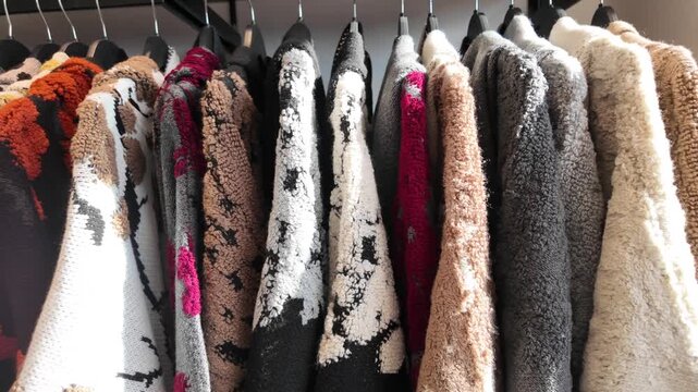 Warm sweaters hang on display in a shop