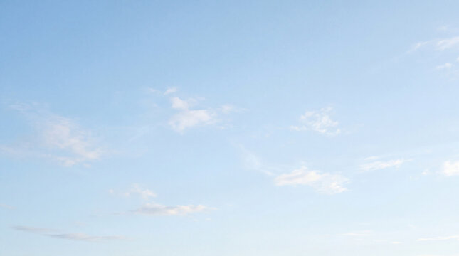 Serene light blue sky with scattered soft white clouds, providing a peaceful and spacious natural background.