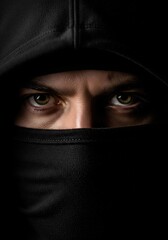Naklejka premium Portrait Of A Man With Intense Green Eyes Wearing A Dark Hooded Face Covering