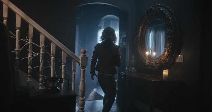Wide, tracking shot following lone woman with flashlight as she explores scary home at night
