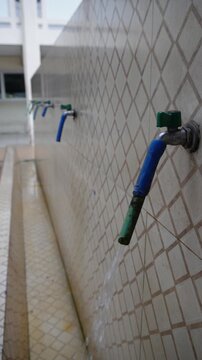 Row of Public Wudu Faucets with Running Water at Mosque - vertical screen