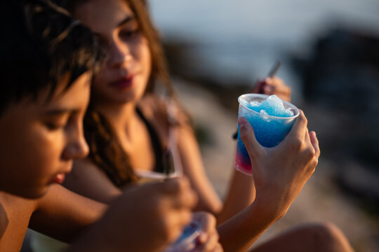 Children enjoying refreshing blue slushy drinks during summer sunset