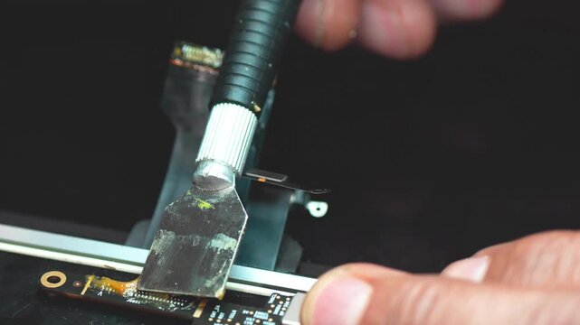 Close-up of technician soldering video connector during precise laptop motherboard repair