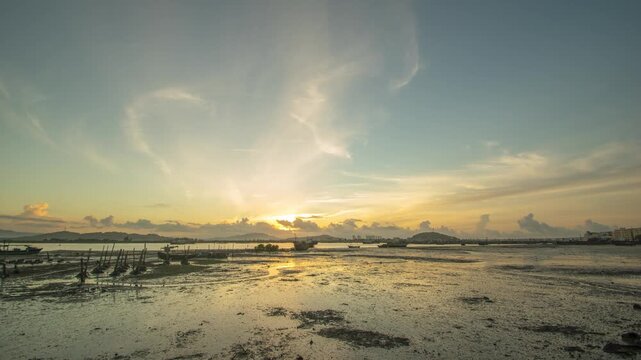 Sunset over coastal mudflat with fishing boats and dramatic clouds
