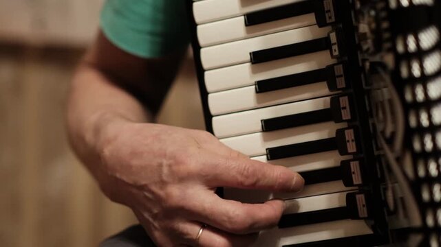 A man plays an accordion in a cozy room. His hands move gracefully over the keys, creating music that fills the air with joy.
