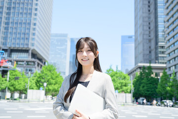 Fototapeta premium ビル街でノートパソコンを使う日本人女性