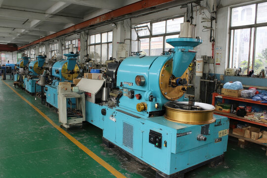 A row of industrial coffee roasters are situated inside of a coffee roasting facility for processing the coffee beans, preparing for distribution