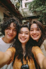 Fototapeta premium Three smiling young friends taking a selfie outdoors with a vintage camera