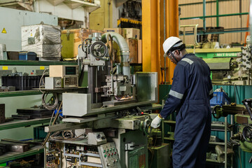 Fototapeta premium African adult man technician stands at machine console, checking condition during automated process supervision, maintenance support, connected workflow, equipment readiness on shop floor line.