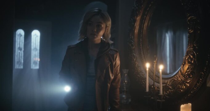 Cautious young woman with flashlight exploring dark home and answering rotary phone - tracking shot