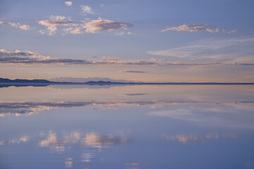 Fototapeta premium A breathtaking symmetrical reflection of sunset clouds on the flooded Salar de Uyuni salt flats in Bolivia. Perfect for travel, wellness, and conceptual backgrounds with ample copy space.
