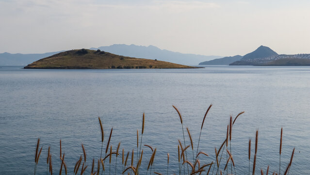 Bitez Bodrum coastline view with island, calm Aegean Sea water, and distant mountains under a clear sky