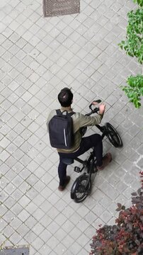 Bicicleta y ciclista pedaleando ejercicio saludable ecol&oacute;gico no contaminante en perspectiva a&eacute;rea cenital desde arriba por acera de adoqu&iacute;n en calle de ciudad