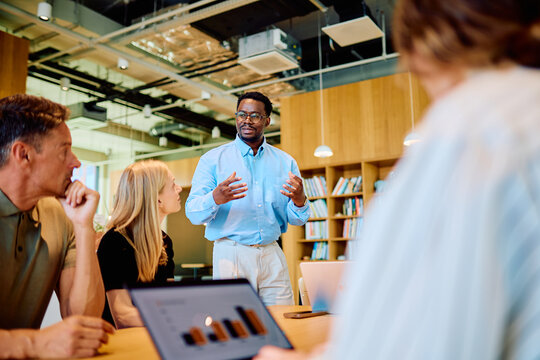Business team meeting in a modern office, an African American man presenting data and discussing strategy with colleagues