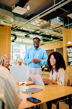 Diverse business professionals conducting a collaborative meeting in a contemporary office setting, sharing ideas and working together happily