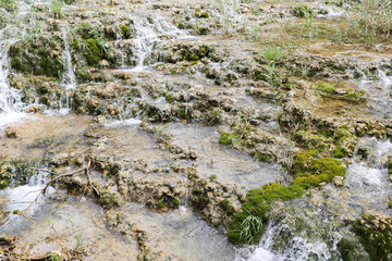 Fototapeta premium Small waterfalls flowing over limestone rocks. Natural river cascade outdoors. Crystal water stream in green environment. Scenic national park scenery background. Fresh nature destination view.