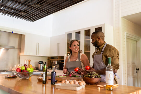Two people cooking together in a modern kitchen, smiling and chatting.