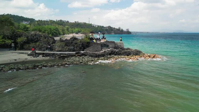 Drone perspective of Batu Bolong temple with ocean waves and coastal scenery Lombok