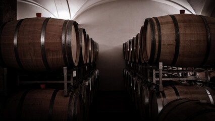 Wine barrels stored in a cellar with dim lighting for aging purposes and organized on racks for easy access © Fleuronica