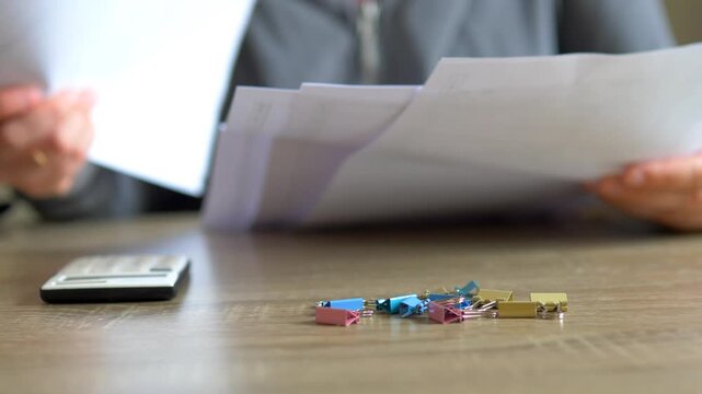 Sorting Paperwork Invoices at Office Desk Close Up &mdash; Colorful Binder Clips Foreground, Bookkeeping Financial Audit and Accountant Workspace