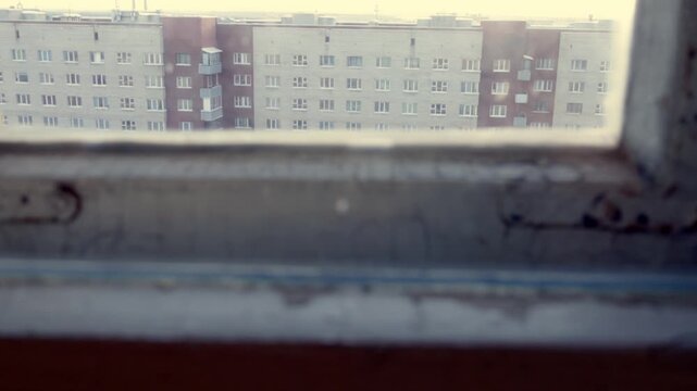 Close-up of a weathered window frame with peeling paint and blurred cityscape. Refocusing from the foreground to the background