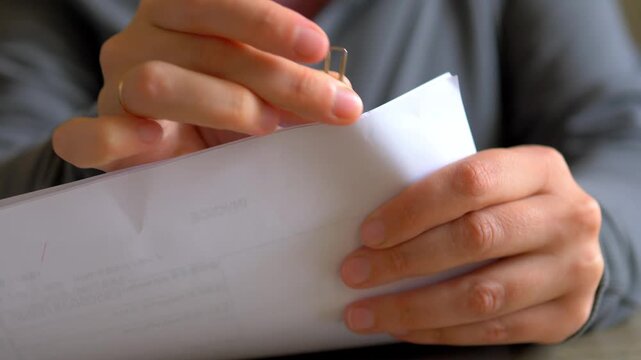 Removing Paper Clip From Financial Documents Close Up &mdash; Hands Sorting Utility Bills, Organizing Invoice Stack and Bookkeeping Office Work
