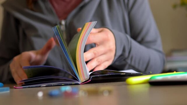 Flipping Book Pages at Workspace Close Up &mdash; Rainbow Color Edges Paper Stack, Open Literature Novel, Studying and Creative Stationery Texture