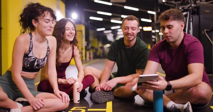 Group of friends sharing fitness tips and exercises at a gym center during morning workout session
