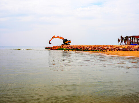 Breakwater construction at coastal. Beach regeneration on sea coastline. Beach renovation. Shore protection. Excavator  coastal protection work, protect beach. Cleaning and dredging