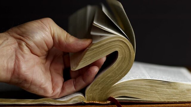 A man flipping through pages of the Bible looking for a scripture