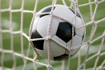 Naklejka premium Soccer ball nestled in net during a competitive match on a sunny day