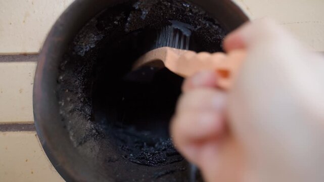 Cleaning chimney pipe from soot and tar buildup with metal wire brush