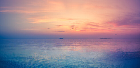 Obraz premium Tranquil panoramic pastel sunset calm ocean sea soft pink purple sky reflection horizon. Dreamy summer paradise escape, exotic vacation relaxation wellness mindfulness travel romantic seascape nature 
