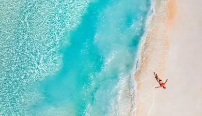 Aerial top view woman relax sunbathing soft sandy shore tropical beach turquoise crystal water white sand summer vacation drone lifestyle paradise getaway serene coastal relaxation wanderlust holiday © icemanphotos