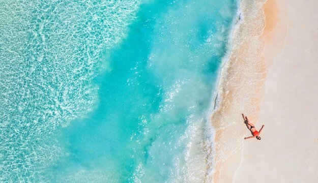 Aerial top view woman relax sunbathing soft sandy shore tropical beach turquoise crystal water white sand summer vacation drone lifestyle paradise getaway serene coastal relaxation wanderlust holiday