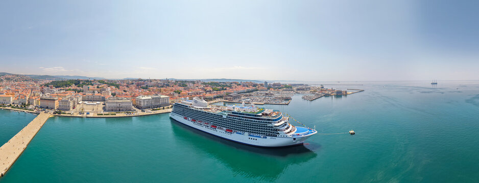 TRIESTE, ITALIA - 9 MAGGIO 2026: Veduta aerea della nave da crociera Oceania  Allura ormeggiata alla Stazione Marittima con lo sfondo del panorama cittadino e del colle di San Giusto.