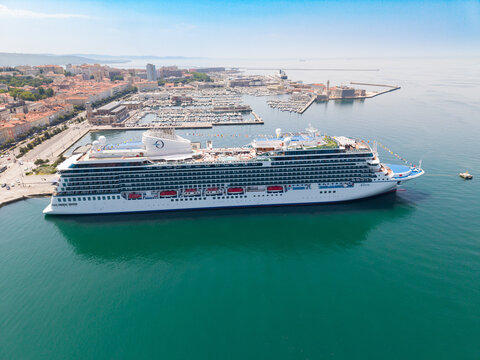 TRIESTE, ITALIA - 9 MAGGIO 2026: Veduta aerea della nave da crociera Oceania  Allura ormeggiata alla Stazione Marittima con lo sfondo del panorama cittadino e del colle di San Giusto.