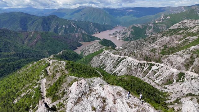 Panoramic view of Kozjak Lake with a mountain landscape in North Macedonia. Sunny day, aerial drone view during flight. People walking and enjoying the scenic views. North Macedonia. 