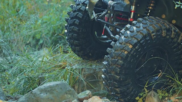 Low angle view of custom 4x4 undercarriage. Large mud terrain tires grip wet rocks while specialized suspension articulates. Concept of extreme offroading, motorsport and outdoor adventure